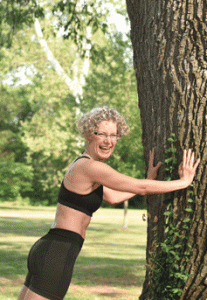 Sally in yoga clothes doing a push-up against a tree.