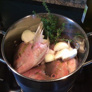 Making broth in a pot with fish heads and vegetables